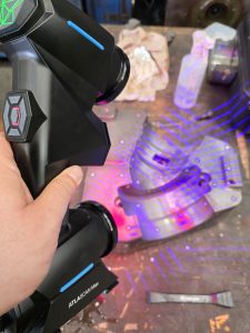 A QCI engineer using a handheld bluelight scanner. The engineer is scanning some moulding tooling using reference scanning dots